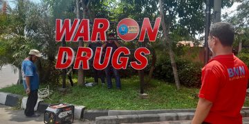 Seorang pegawai BNN Kota Surabaya mengawasi pekerjaan huruf timbul War on Drugs di Kawasan Taman Pelangi, Surabaya, 24 Maret 2022. Dok: Lines Jatim.