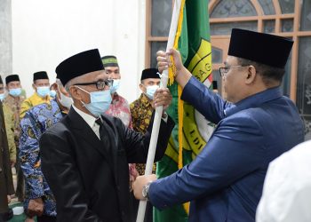 Ketua DPD LDII Pamekasan M Bakir (kiri) menerima panji LDII dalam pelantikan Pengurus DPD LDII Pamekasan, 22 Maret 2022 . Dok: Lines Pamekasan.