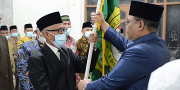 Ketua DPD LDII Pamekasan M Bakir (kiri) menerima panji LDII dalam pelantikan Pengurus DPD LDII Pamekasan, 22 Maret 2022 . Dok: Lines Pamekasan.