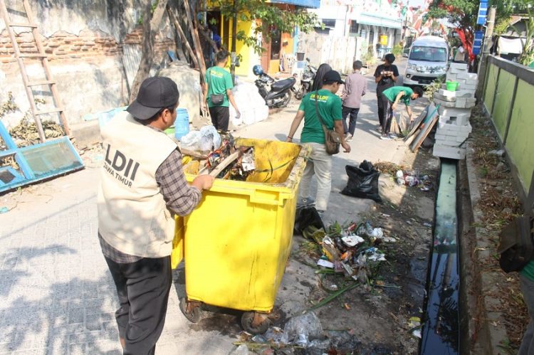 Sejumlah warga LDII gotong royong membersihkan selokan di sekitar Tempat Pemakaman Umum (TPU) di Jalan Gayungan I, Surabaya, Jumat (4/8). Dok: LINES.