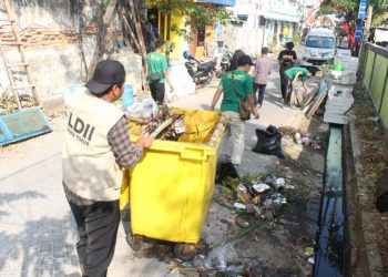 Sejumlah warga LDII gotong royong membersihkan selokan di sekitar Tempat Pemakaman Umum (TPU) di Jalan Gayungan I, Surabaya, Jumat (4/8). Dok: LINES.