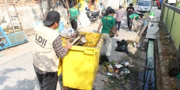 Sejumlah warga LDII gotong royong membersihkan selokan di sekitar Tempat Pemakaman Umum (TPU) di Jalan Gayungan I, Surabaya, Jumat (4/8). Dok: LINES.