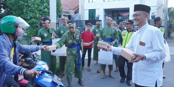 Ketua PC LDII Kecamatan Gunung Anyar, Giyato (kanan) bagikan takjil pada pengendara di kawasan jalan raya Ir Soekarno (MERR) Surabaya, Minggu (24/3). Dok: LINES.