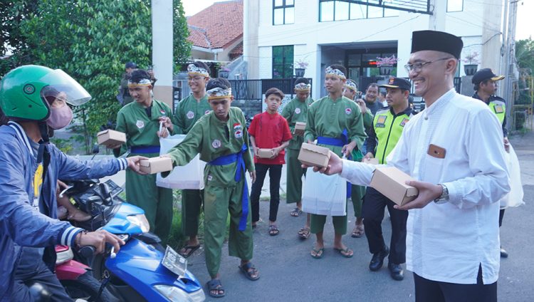 Ketua PC LDII Kecamatan Gunung Anyar, Giyato (kanan) bagikan takjil pada pengendara di kawasan jalan raya Ir Soekarno (MERR) Surabaya, Minggu (24/3). Dok: LINES.